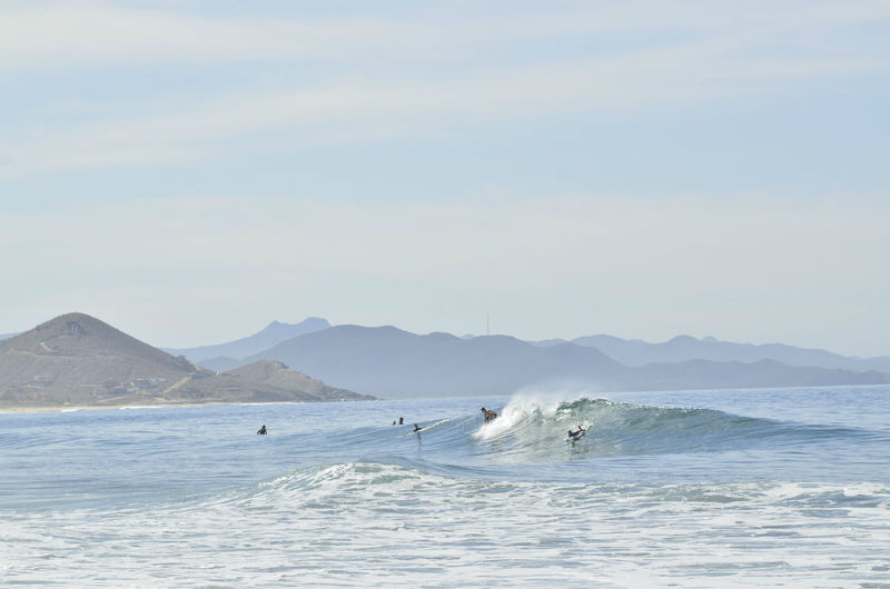 Surfers ride a wave in the pacific ocean off the coast of baja california sur, pescadero, mexico