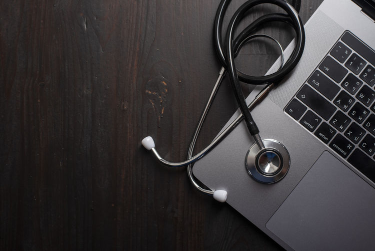 Close-up of laptop with stethoscope on wooden table