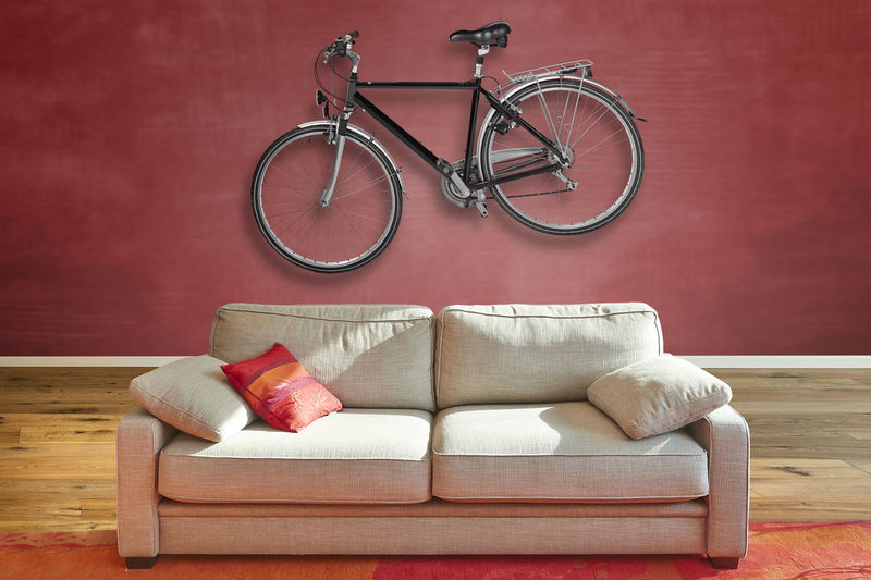 Elegant classical sofa from front in luxurious apartment with a hanging road bike on wall.