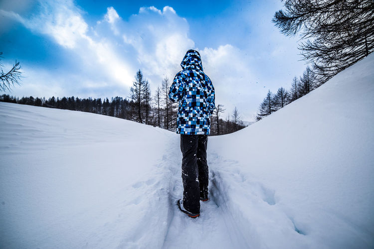 Person standing of snow covered landscape against sky