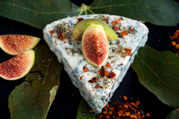 High angle view of fig slices and cheese on black background