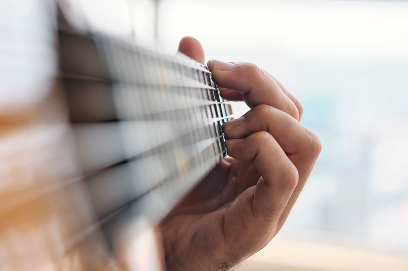 Close-up of hand playing guitar at home