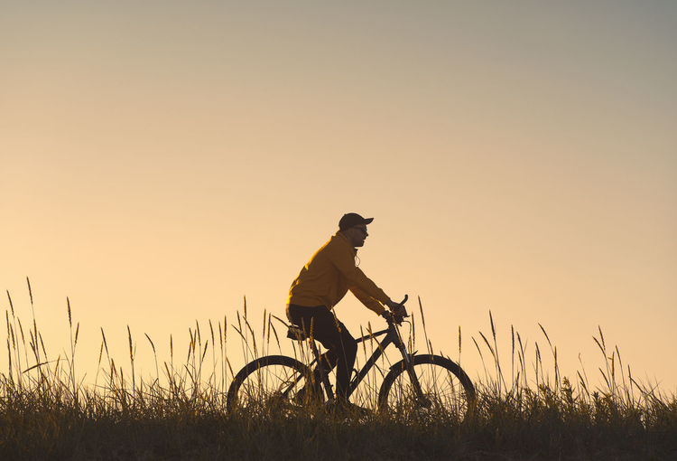 Silhouette of a cyclist. he rides through the meadow.
