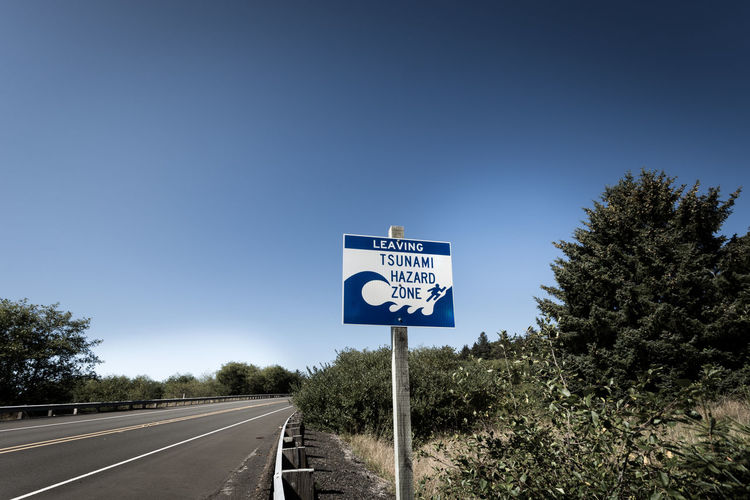 Road sign against clear blue sky