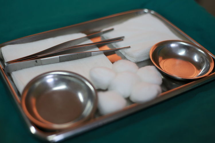 High angle view of cotton balls and equipment with bowls in tray on table in hospital