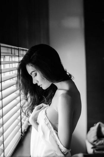 Side view of sensuous woman standing at window