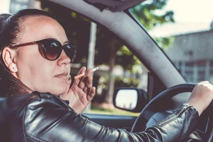 Portrait of woman wearing sunglasses sitting in car