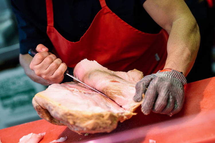 Midsection of chef cutting meat in kitchen