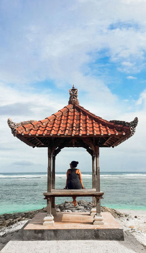Man sitting on roof against sea