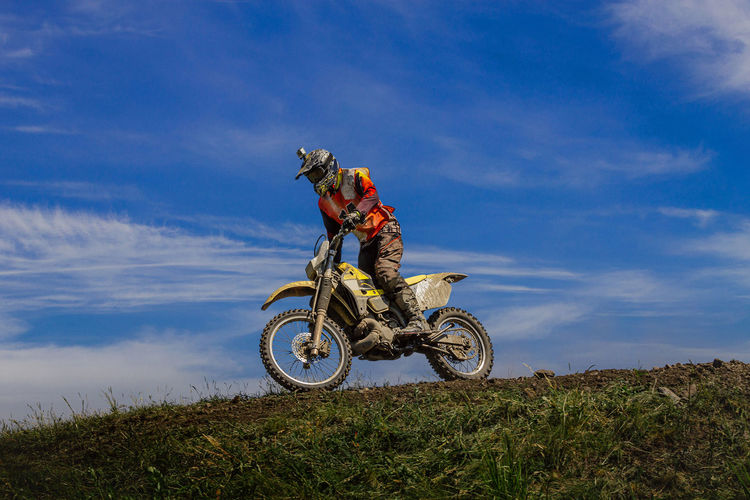 Enduro motorcycle racer on mountain in background blue sky