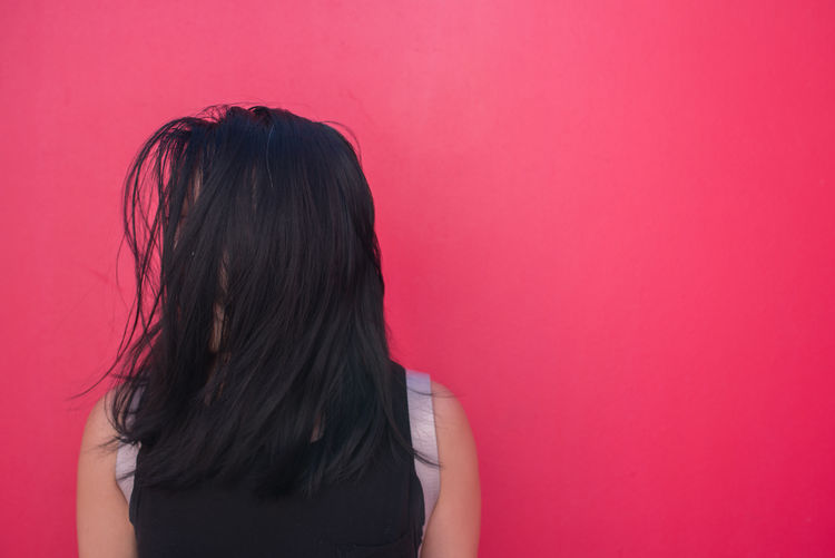 Woman with black hair against pink background