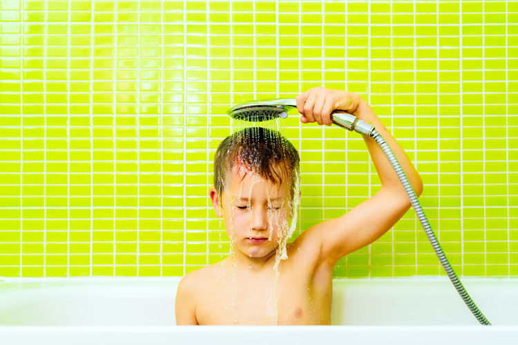Disgusted expression of a young boy taking a shower and washing himself angrily.