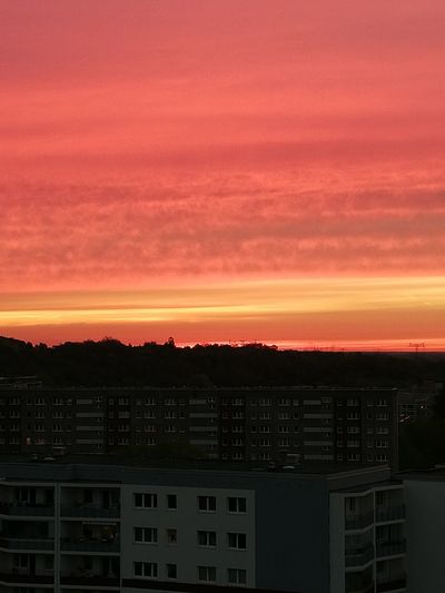 Silhouette buildings against dramatic sky during sunset