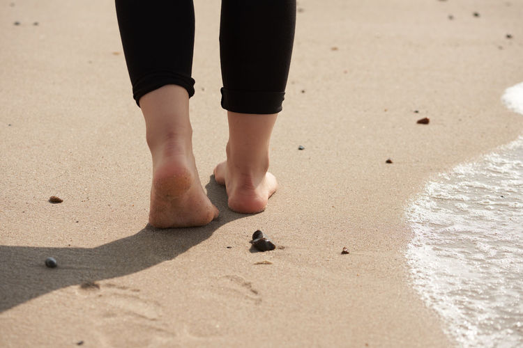 Low section of woman walking on sand