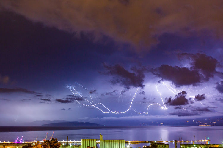 Lightning over trees against sky at night