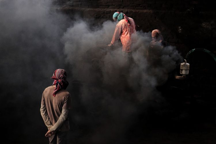 Rear view of people working at brick field in a over polluted environment 