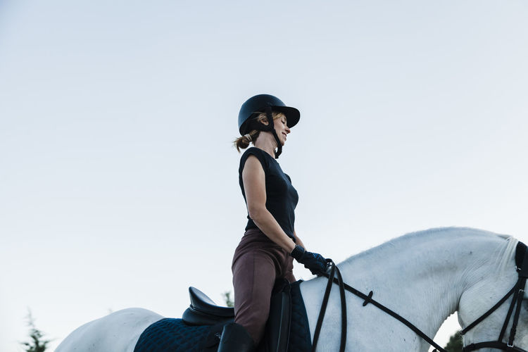 Low section of person riding horse against sky