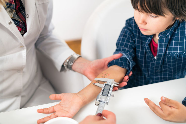 Close-up of doctor performing immunology therapy on hand of boy 