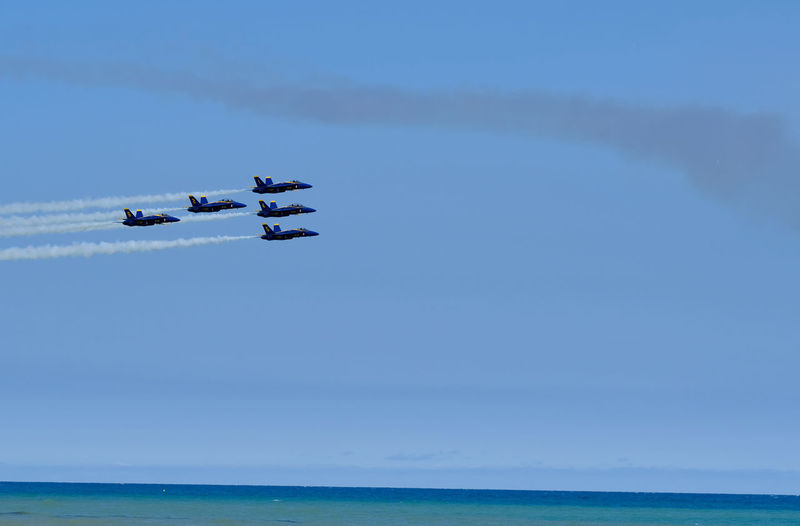 Airplane flying over sea against blue sky