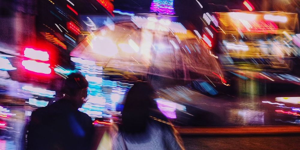 Blurred motion of people walking in illuminated city at night