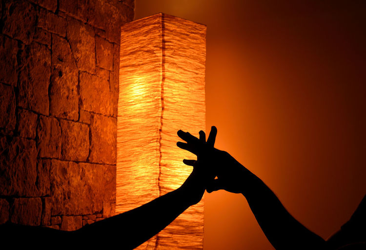 Hands of lovers on a background of orange light