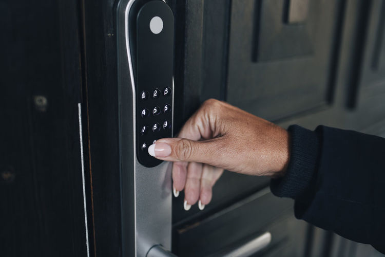 Cropped hand of woman unlocking combination security code on house door