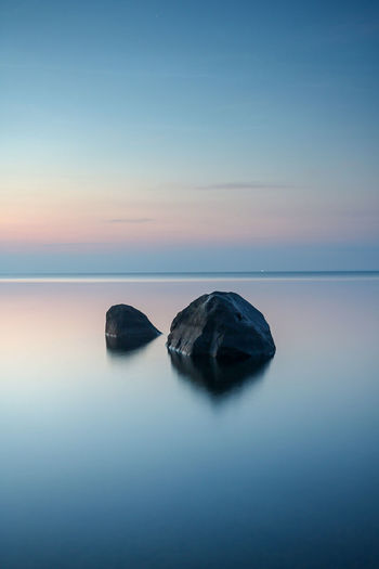 Rocks on sea against sky during sunset