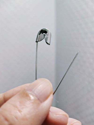 Close-up of hand holding safety pin