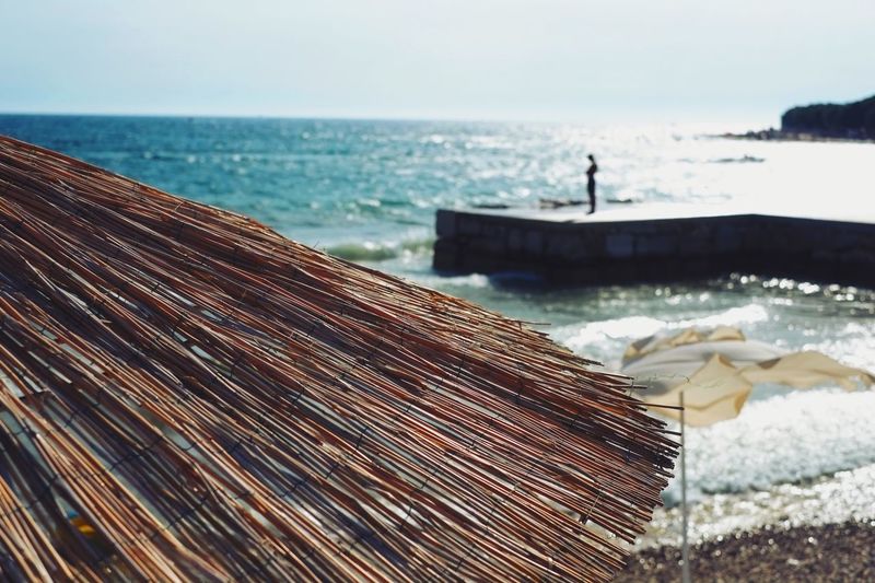 Close-up of thatched roof against beach