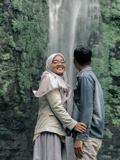 Smiling woman standing with man against waterfall
