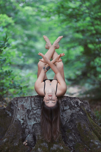 Young woman exercising while lying on rock