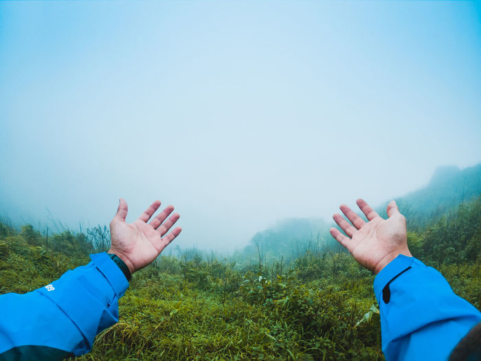 Cropped hands against sky during foggy weather