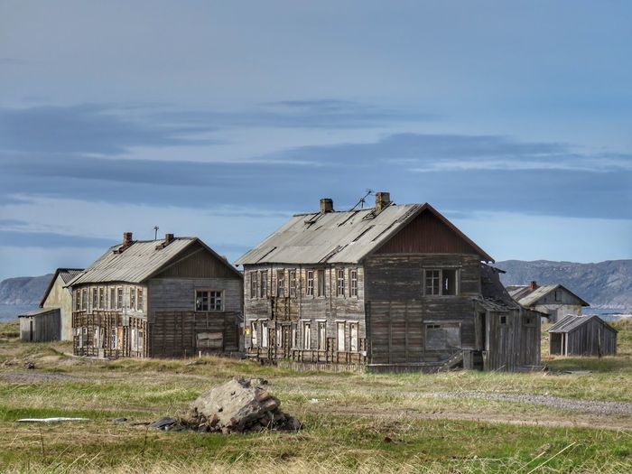 Old houses on field against sky