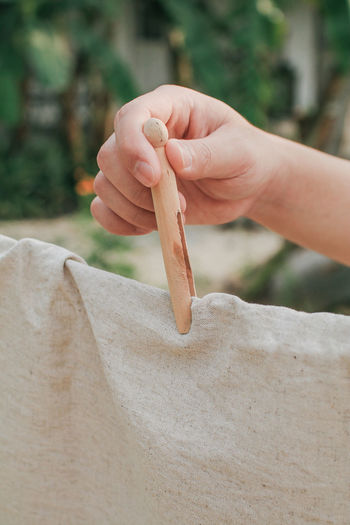 Cropped hand of child holding clothespin on textile