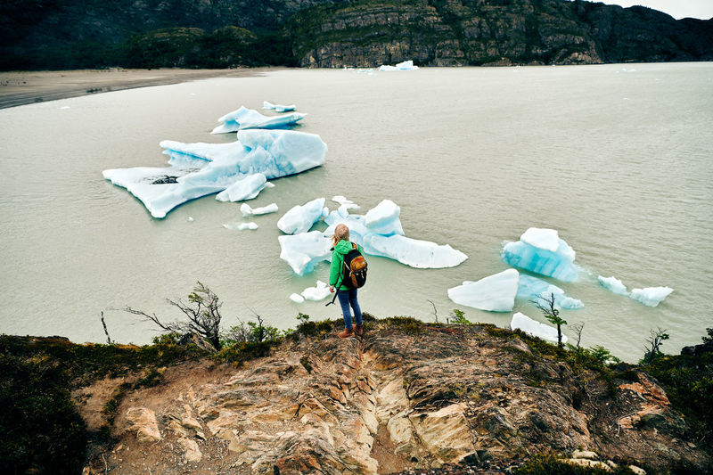 High angle view of woman standing overlooking icebergs at lago grey in patagonia, chile