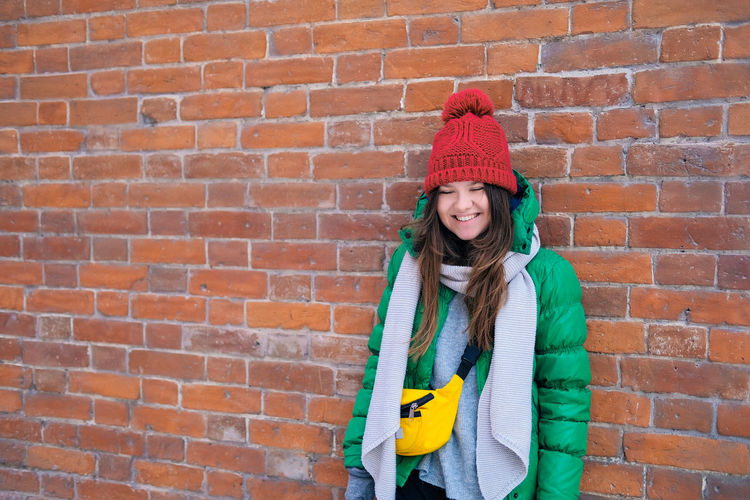 Portrait of smiling woman standing against brick wall