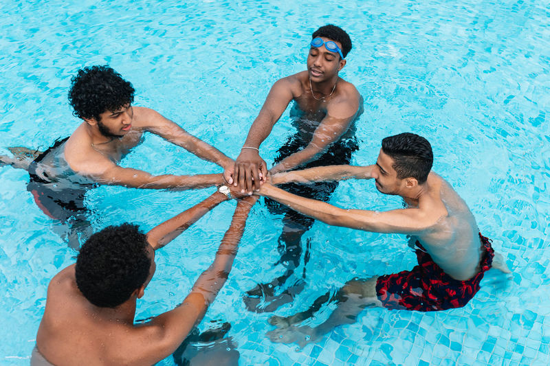Group of young people gathering their hands in a circle inside a pool