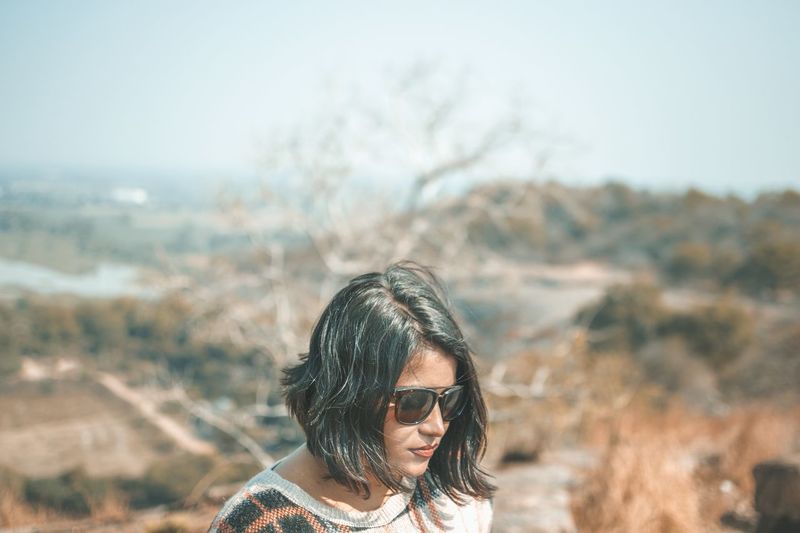 Woman wearing sunglasses against landscape and sky