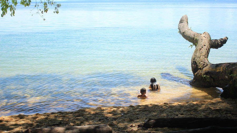 Two children showered at poso lake with a beautiful view and clear water