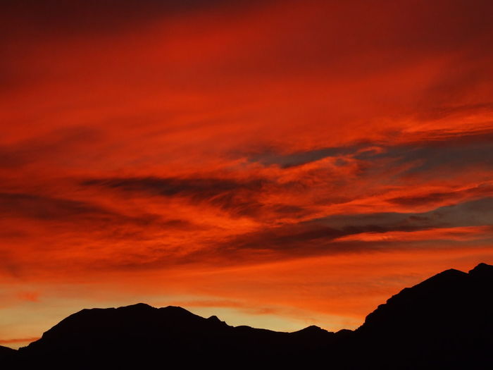 Low angle view of silhouette mountains against orange sky