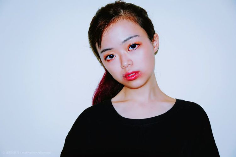 Portrait of young woman with smudged lipstick against white background
