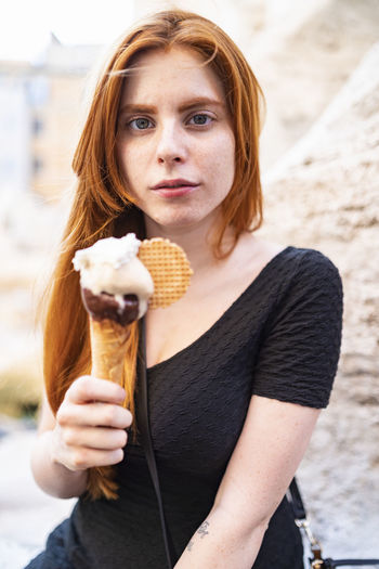 Calm redhead woman with ice cream cone looking at camera
