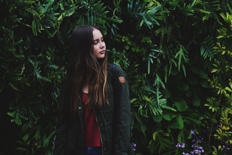 Teenage girl standing by plants at park