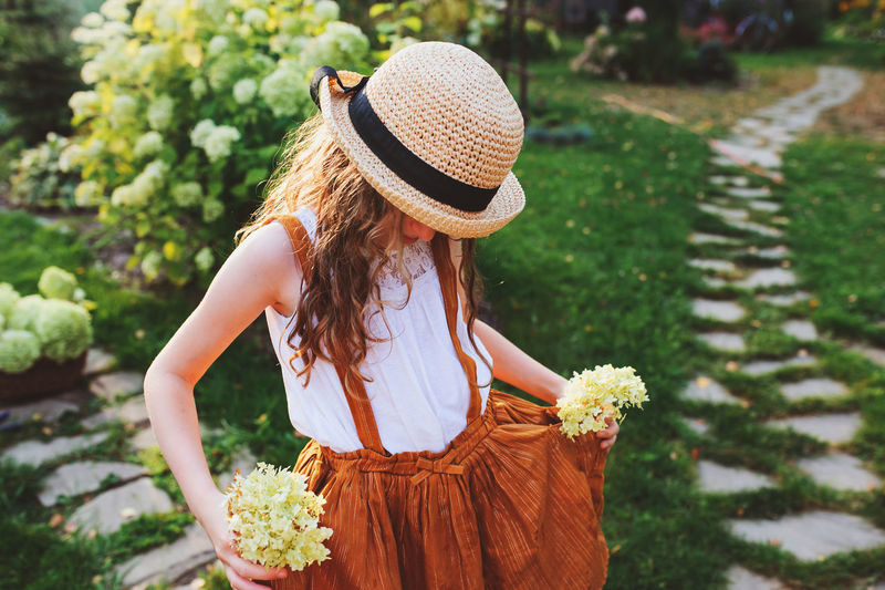 Girl holding flowers while standing in yard