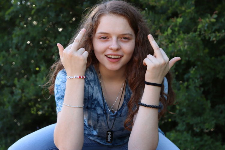 Girl with brown hair giving the middle finger.   smiling 