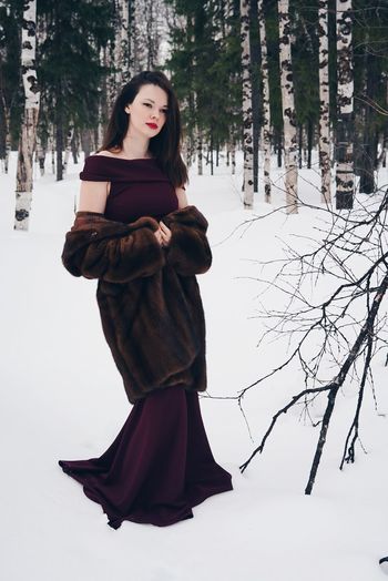 Beautiful young woman wearing dress while standing on snow