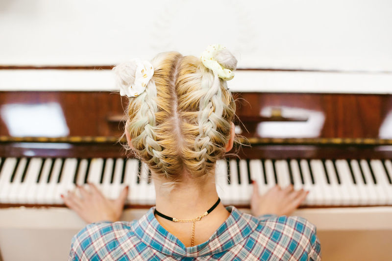 Rear view of woman playing piano at home