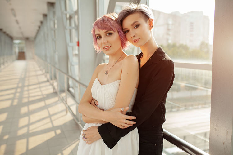 Portrait of young lesbians embracing at corridor in building