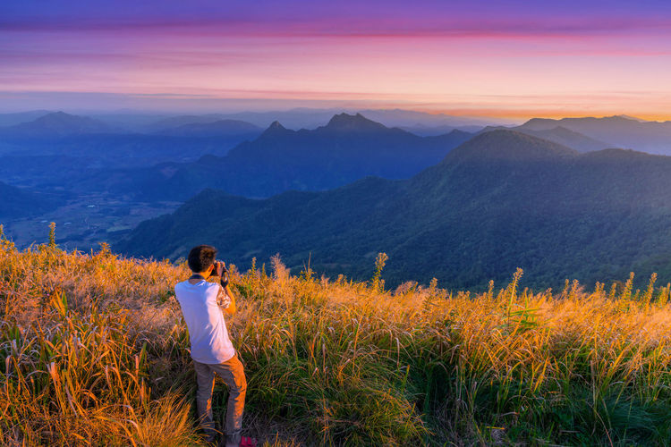 Rear view of woman standing on mountain against sky