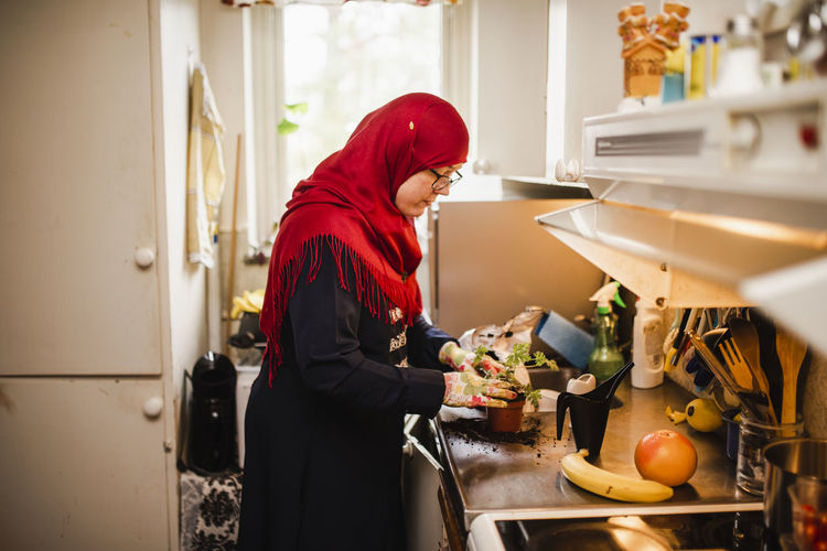 Woman in kitchen potting plant